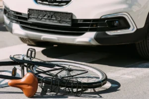 bicycle laying on side next to a car that hit a bicyclist who was riding across the street and will need to file a personal injur claim with assitance from a bicycle accident lawyer