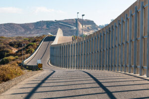 US border divided by fence next to California road