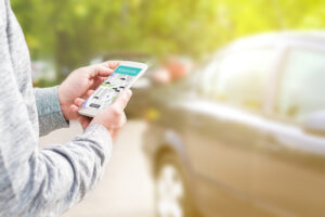 man holding smartphone with rideshare app open while waiting for Uber driver or Lyft driver to pick him up outside