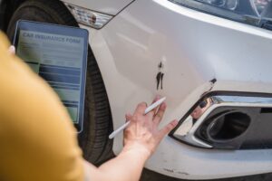 man filling out car insurance claim after a car accident in California to recover damages