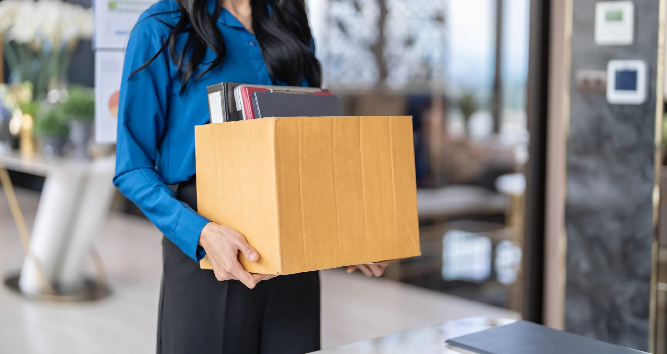 female employee holding box full of belongings after being fired or terminated from her job