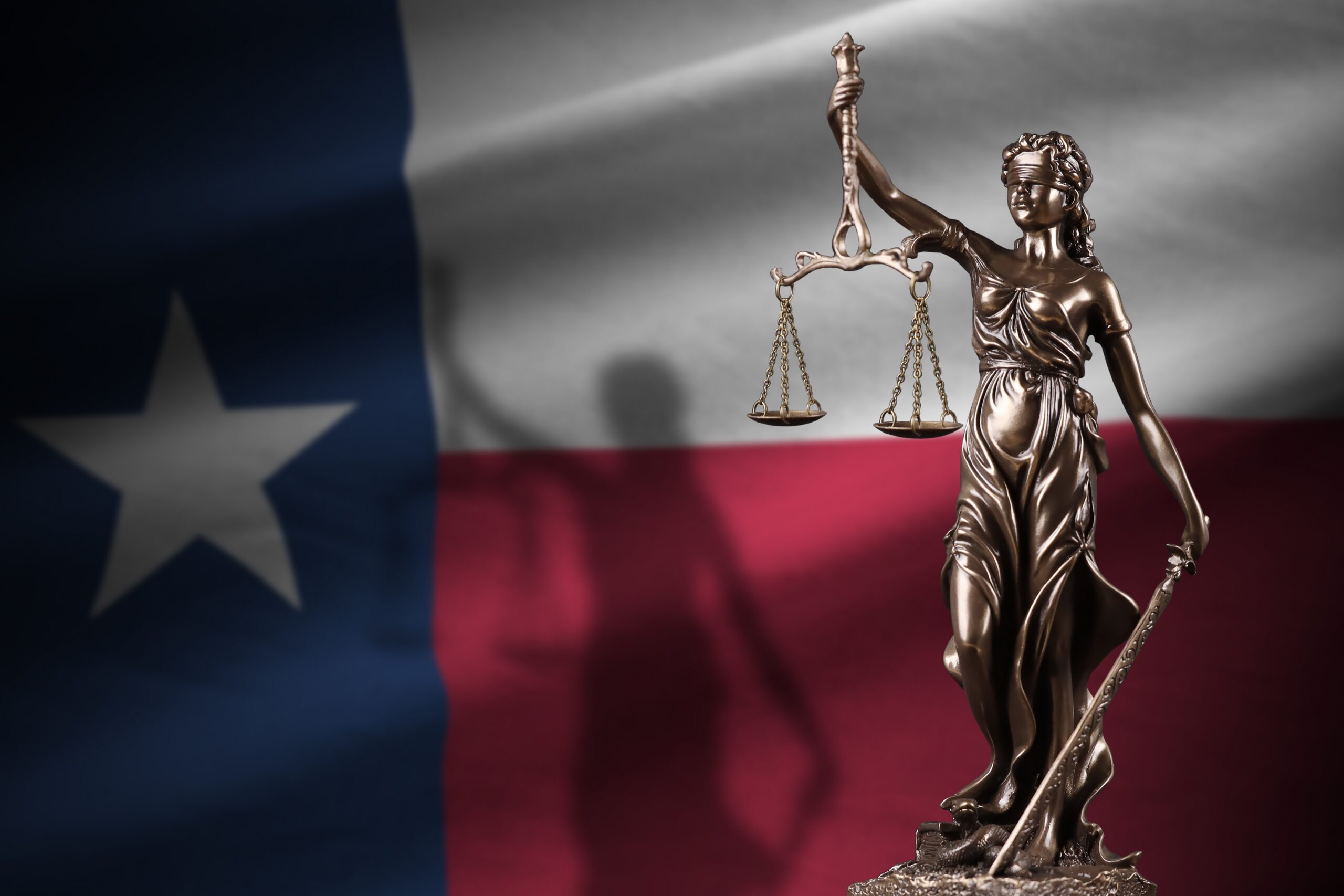Lady Justice in front of the Texas flag to represent the legal framework of the state and injured victims' rights following a personal injury accident.