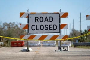 Road closure sign posted after a crash, causing lane closures, traffic delays, and damages to the involved parties.